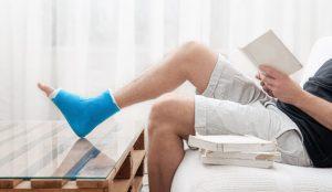 man with broken leg cast reads books against light background interior room 300x174 - Blog